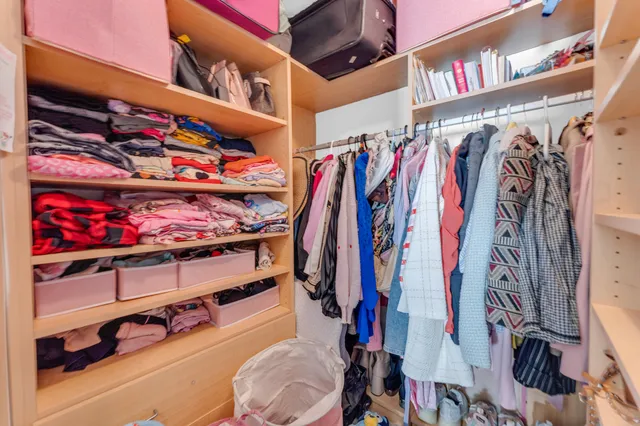 a view of walk in closet with clothes and shoes