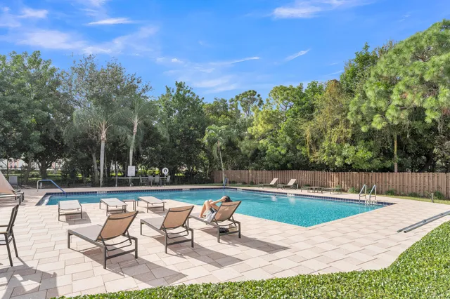a view of swimming pool with seating space and trees in the background