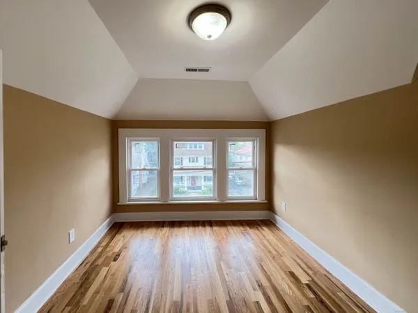 an empty room with wooden floor and windows
