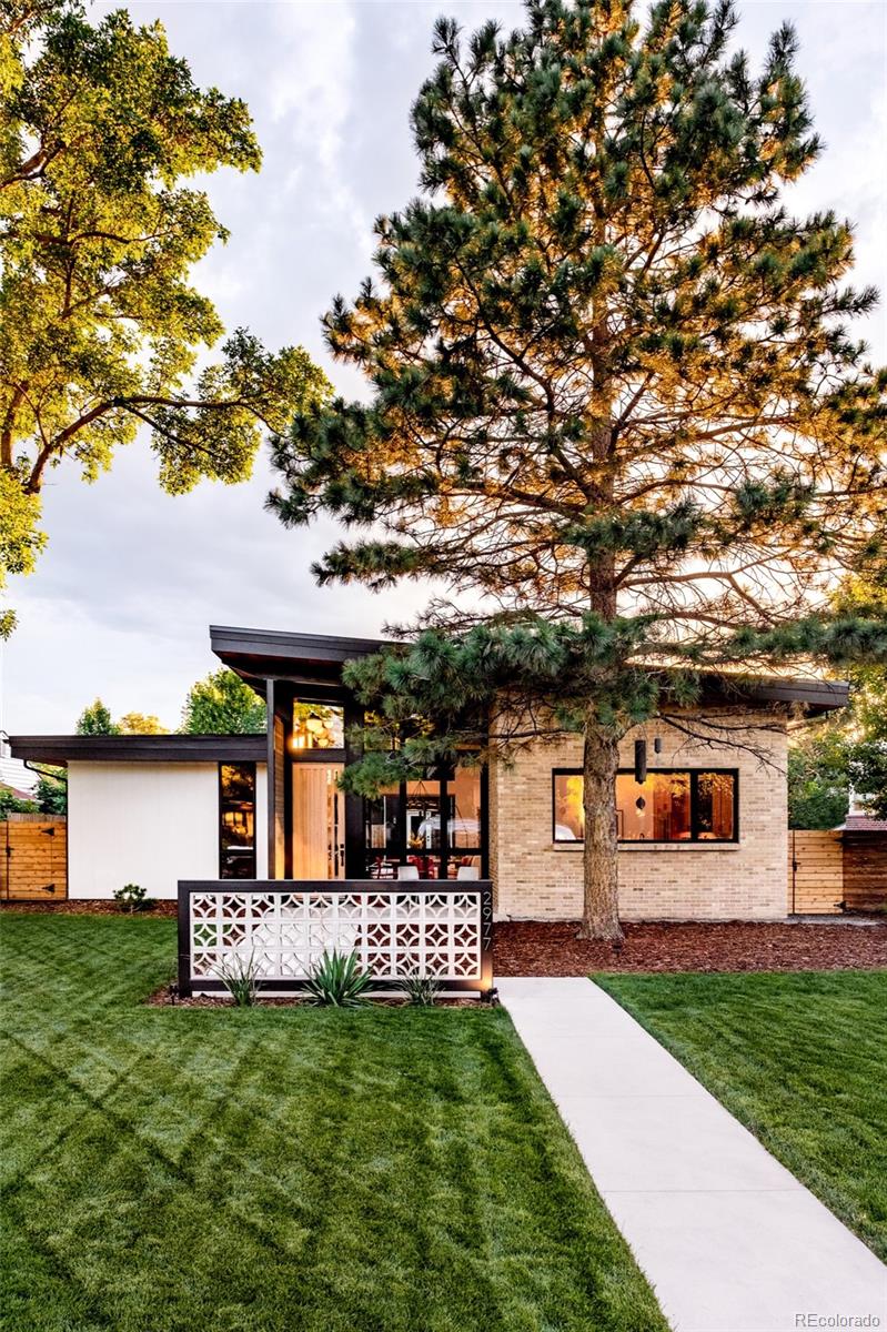 2977 Forest Street Denver, CO 80207 - Photo 21 of 23 a front view of a house with a garden and a tree