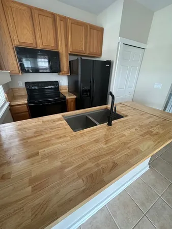 a kitchen with granite countertop wooden cabinets and refrigerator