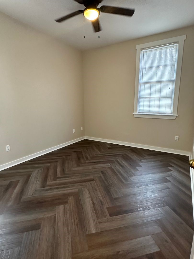 1896 Floyd Street Fernandina Beach, FL 32034 - Photo 3 of 16 an empty room with wooden floor chandelier fan and windows