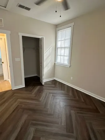 an empty room with wooden floor and windows