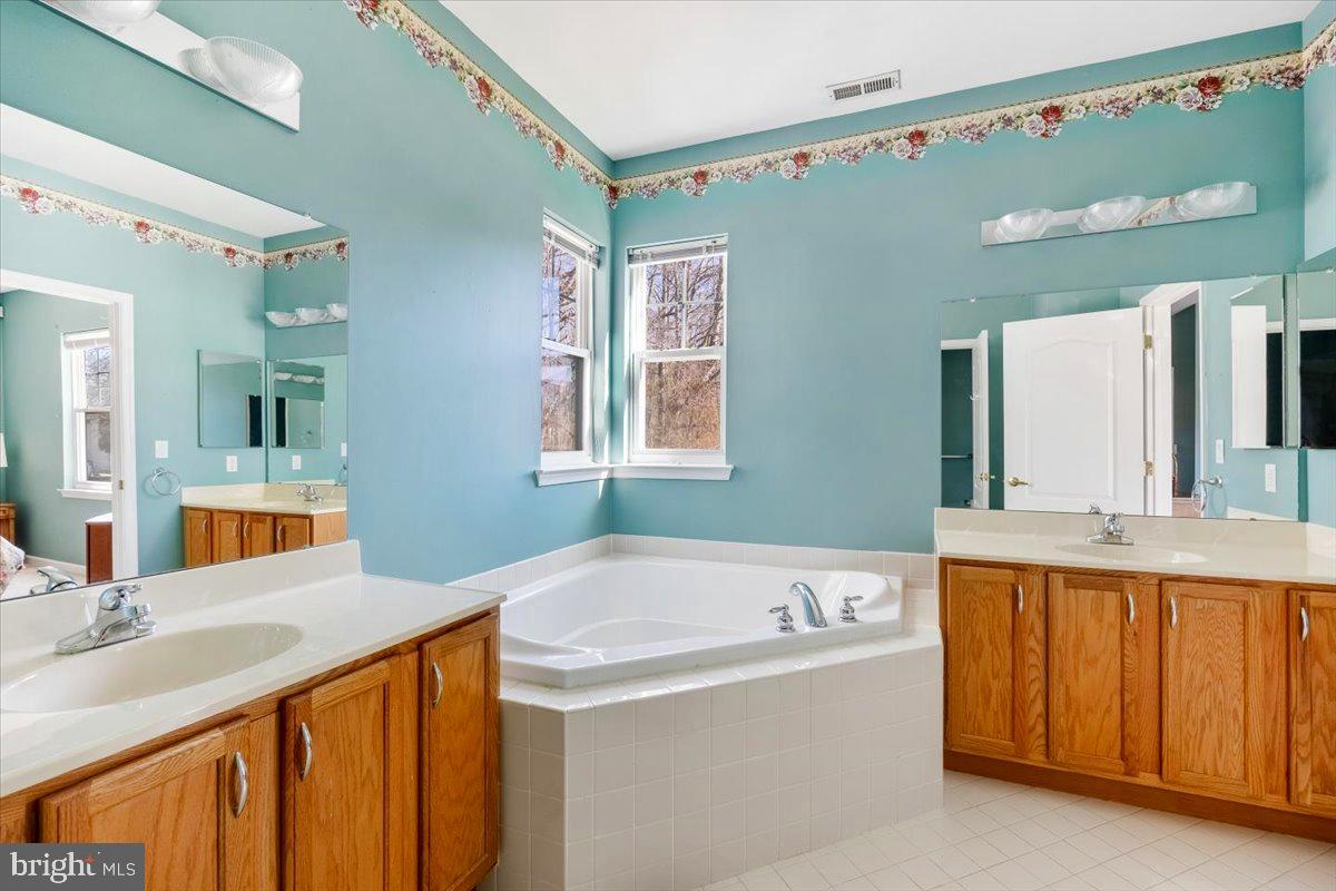 131 Lowell Drive Marlton, NJ 08053 - Photo 33 of 60 a bathroom with a tub a double vanity sink and mirror