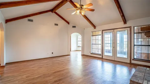 a view of an empty room with window and wooden floor