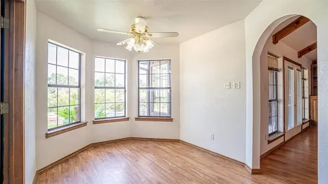 an empty room with wooden floor fan and windows