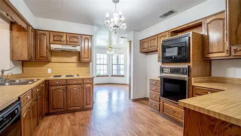 a kitchen with stainless steel appliances granite countertop hardwood floor sink stove and wooden cabinets