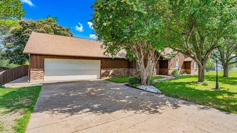 a front view of a house with a garden and trees
