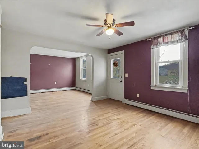 a view of an empty room with window and chandelier fan