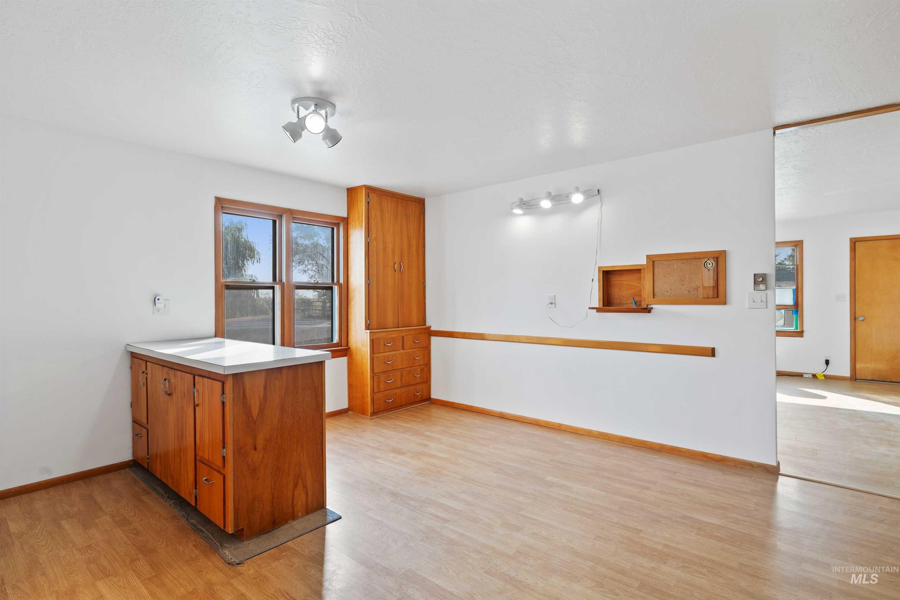 321 Clear Lakes Road Buhl, ID 83316 - Photo 8 of 34 Wood-finish flooring, built-in wooden cabinetry, white countertops, track lighting, and a double-pane window