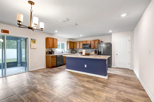 a open kitchen with stainless steel appliances granite countertop a refrigerator a sink dishwasher and a stove with wooden floor