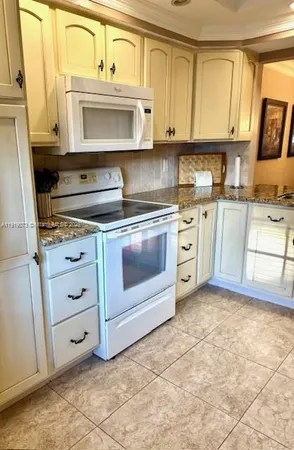 a kitchen with granite countertop a stove top oven microwave and cabinets