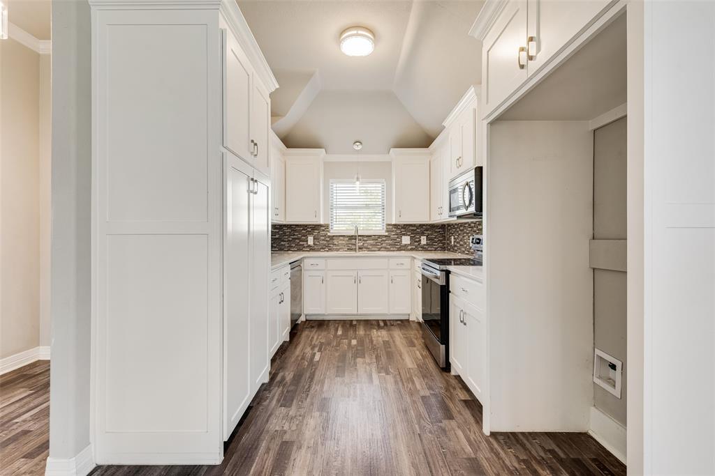 625 Copenhavr Street Pilot Point, TX 76258 - Photo 6 of 20 Kitchen with lofted ceiling, decorative backsplash, white cabinetry, appliances with stainless steel finishes, and dark wood-style floors