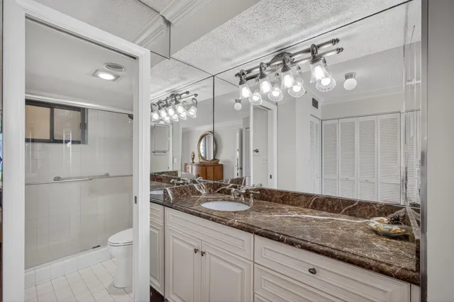 a bathroom with a granite countertop sink a toilet a mirror and shower