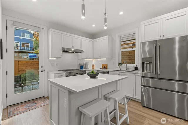 a kitchen with stainless steel appliances granite countertop a refrigerator a sink a stove a dining table and chairs