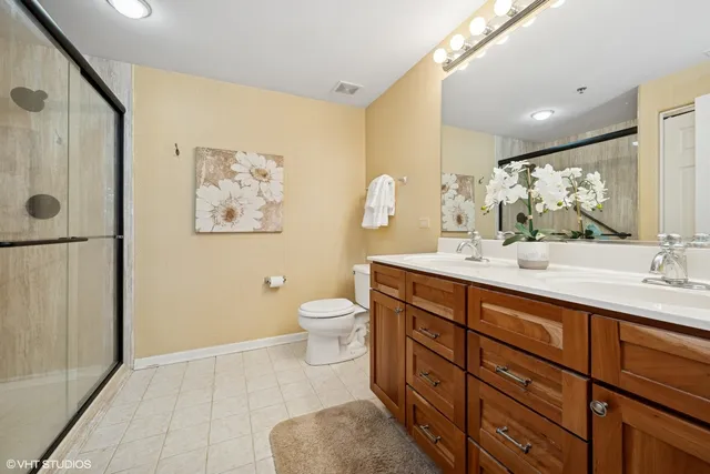 a spacious bathroom with a double vanity sink toilet and a mirror