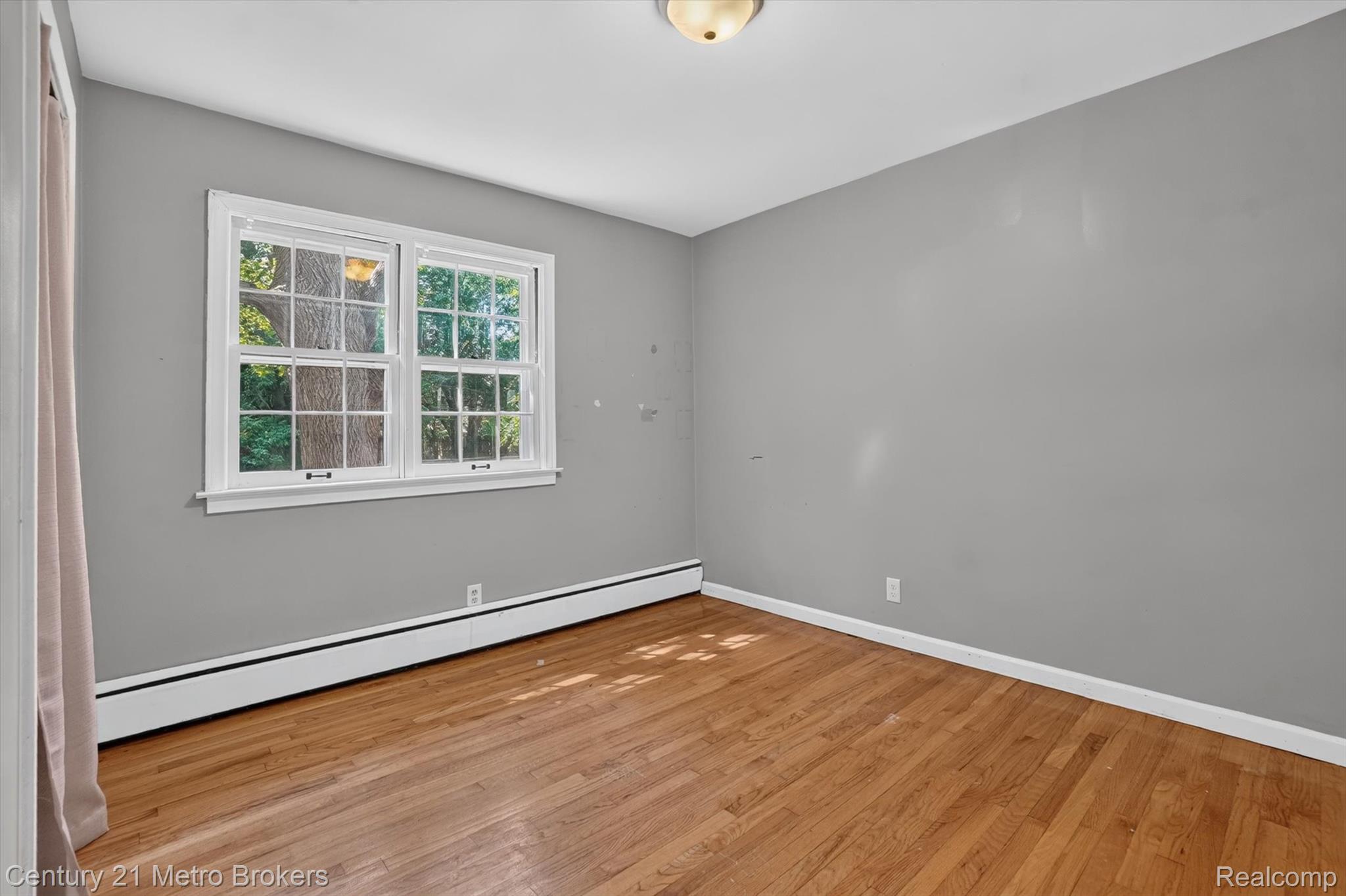4575 Brockway Road Saginaw, MI 48638 - Photo 22 of 44 Hardwood flooring, painted walls, window with grilles, baseboard heating, and ceiling-mounted light fixture