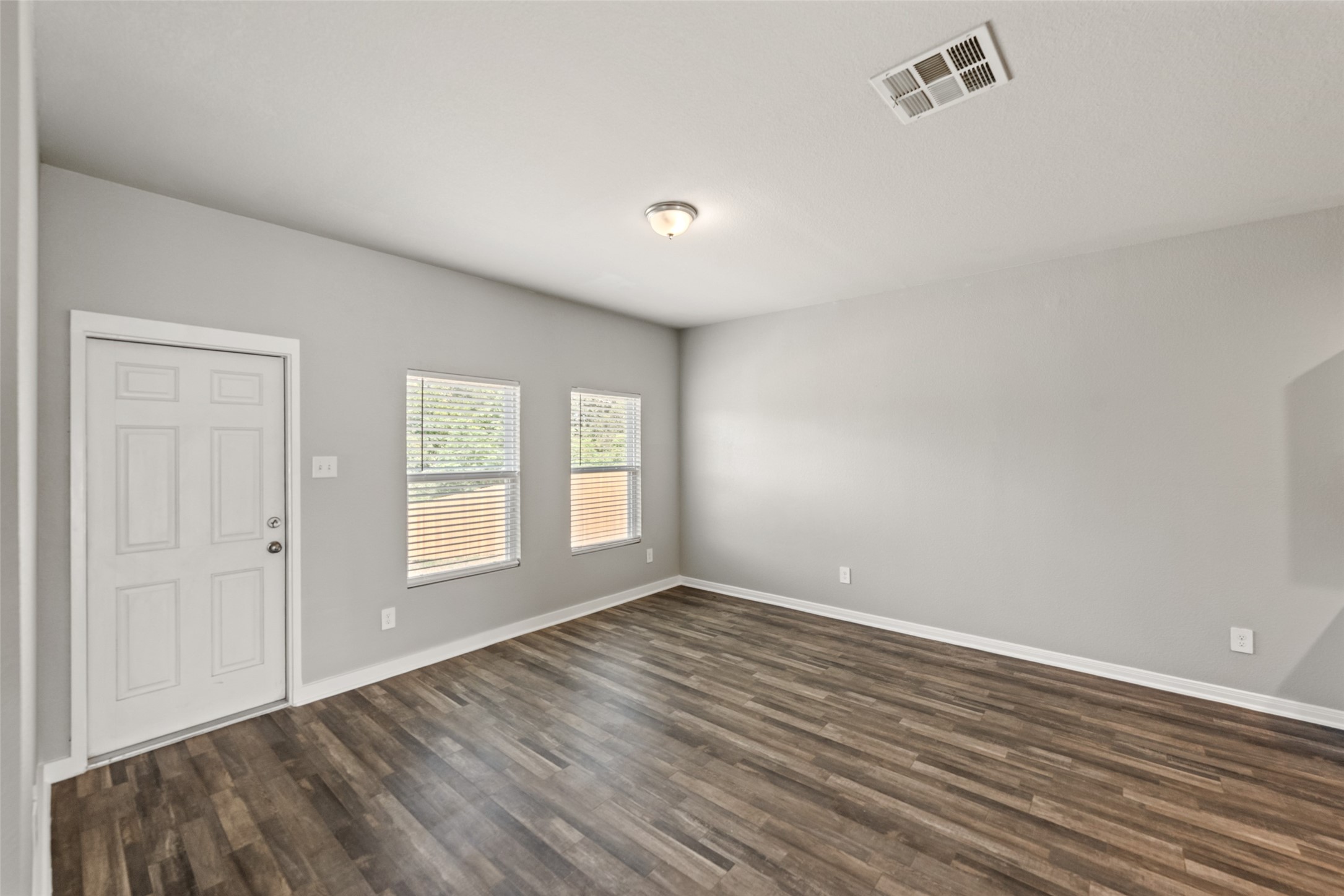 2537 18th Street Hempstead, TX 77445 - Photo 8 of 28 Spacious living area featuring durable wood-look flooring, neutral finishes, and multiple windows providing natural light.