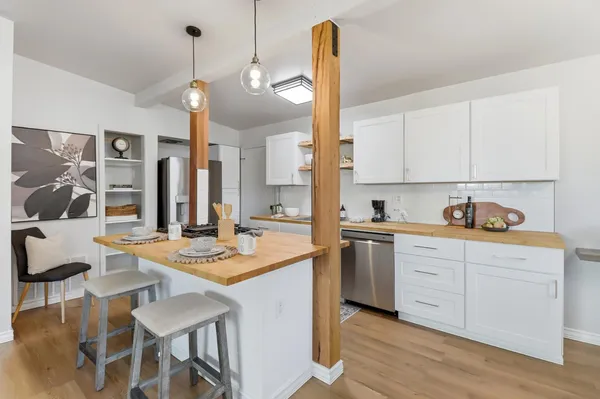 a kitchen with a stove a sink a dining table and chairs with wooden floor