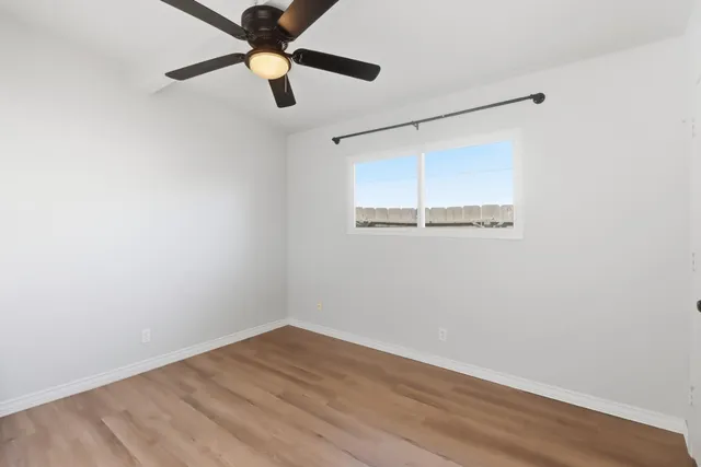 an empty room with wooden floor and a ceiling fan