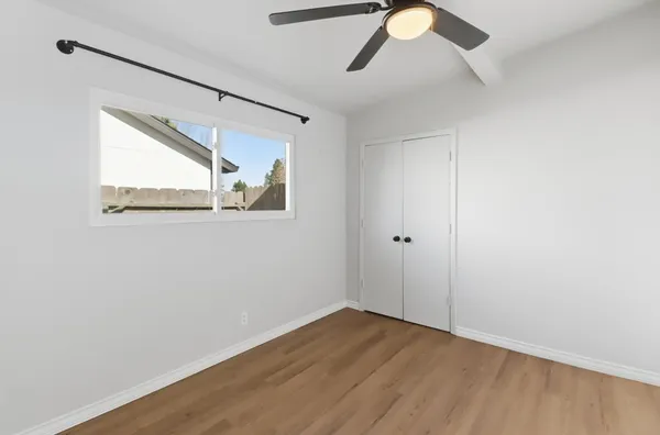 a view of empty room with wooden floor and fan