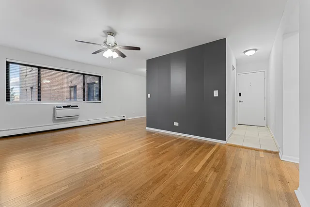 a view of an empty room with window and wooden floor