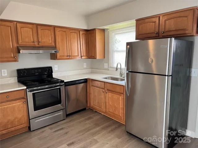 a kitchen with granite countertop a refrigerator stove top oven and cabinets