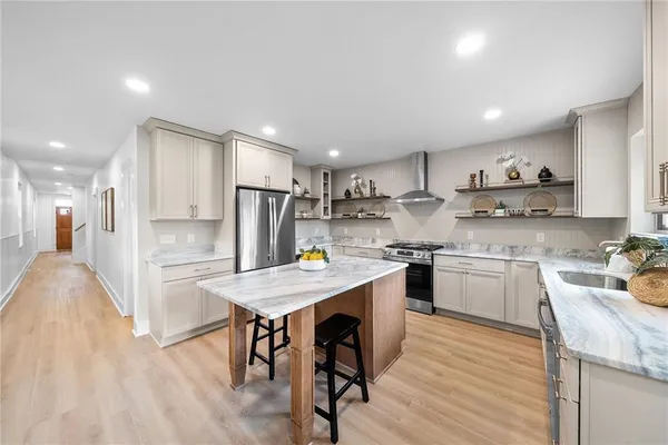 a kitchen with a sink a stove a refrigerator and white cabinets with wooden floor