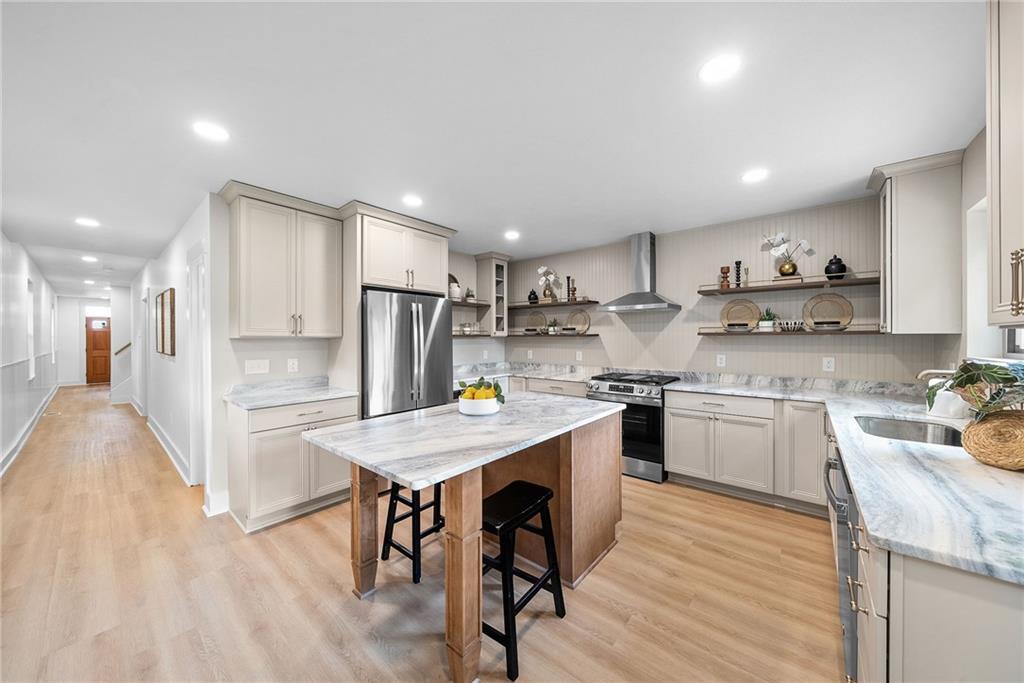 1431 Adams Street Pittsburgh, PA 15233 - Photo 9 of 42 a kitchen with a sink a stove a refrigerator and white cabinets with wooden floor