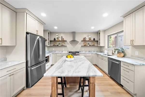 a kitchen with a refrigerator a sink a stove a dining table and chairs