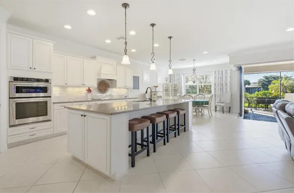 a kitchen with stainless steel appliances granite countertop a stove top oven a sink dishwasher a dining table and chairs with white cabinets