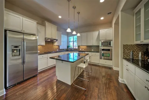 a kitchen with stainless steel appliances a refrigerator a sink a stove a microwave and wooden floors