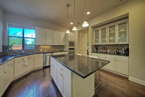 a kitchen with stainless steel appliances granite countertop a sink a stove and a wooden floors