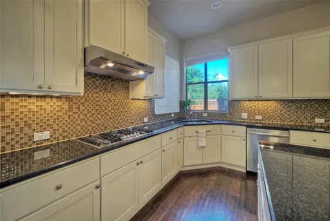 a kitchen with granite countertop cabinets stainless steel appliances a sink and a window