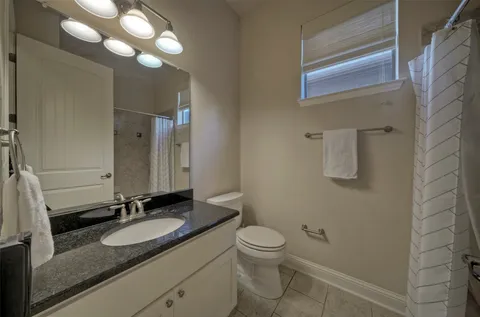 a bathroom with a granite countertop sink a toilet and a mirror