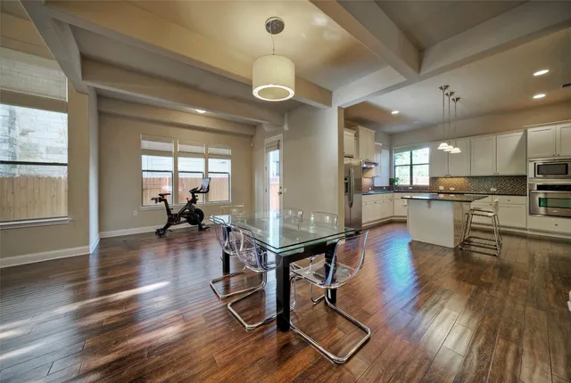 an open kitchen with granite countertop a stove and white cabinets with wooden floor