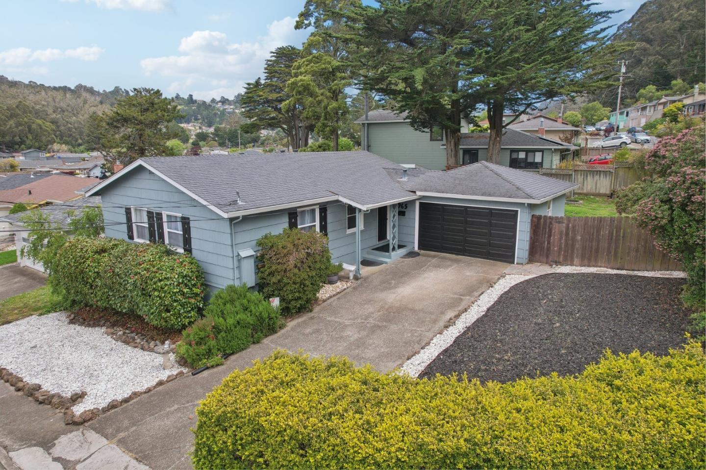 a front view of a house with a garden and trees