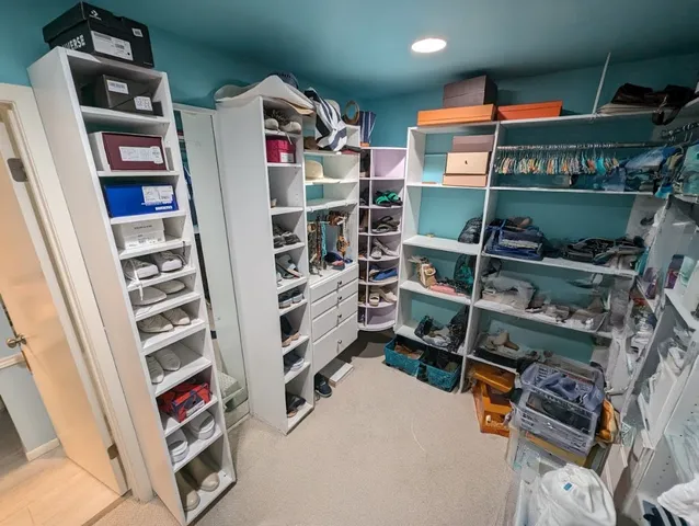 a view of walk in closet with clothes and shoes