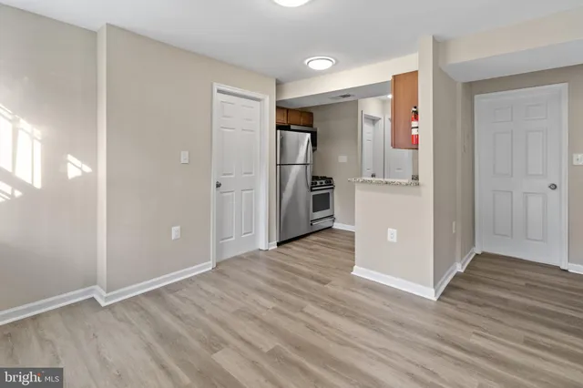 a view of an empty room with kitchen and a window