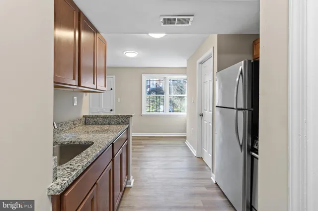 a kitchen with kitchen island granite countertop wooden cabinets a refrigerator and a sink