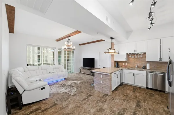 a large white kitchen with stainless steel appliances granite countertop a stove and white cabinets