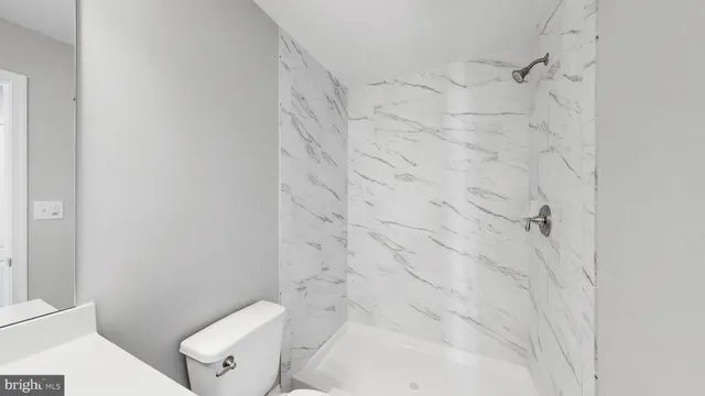 a white toilet sitting next to a shower