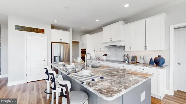 a kitchen with granite countertop kitchen island stainless steel appliances a sink refrigerator and white cabinets