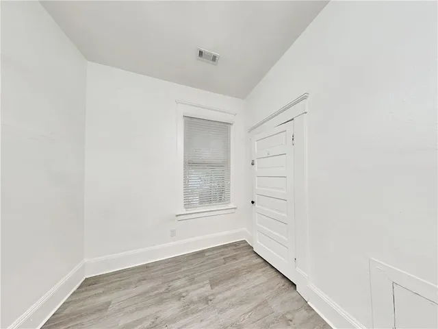 a view of an empty room with wooden floor and closet