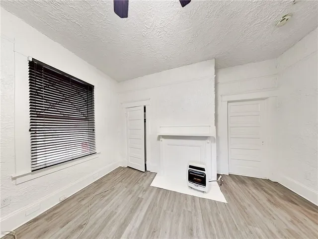 an empty room with wooden floor closet and windows