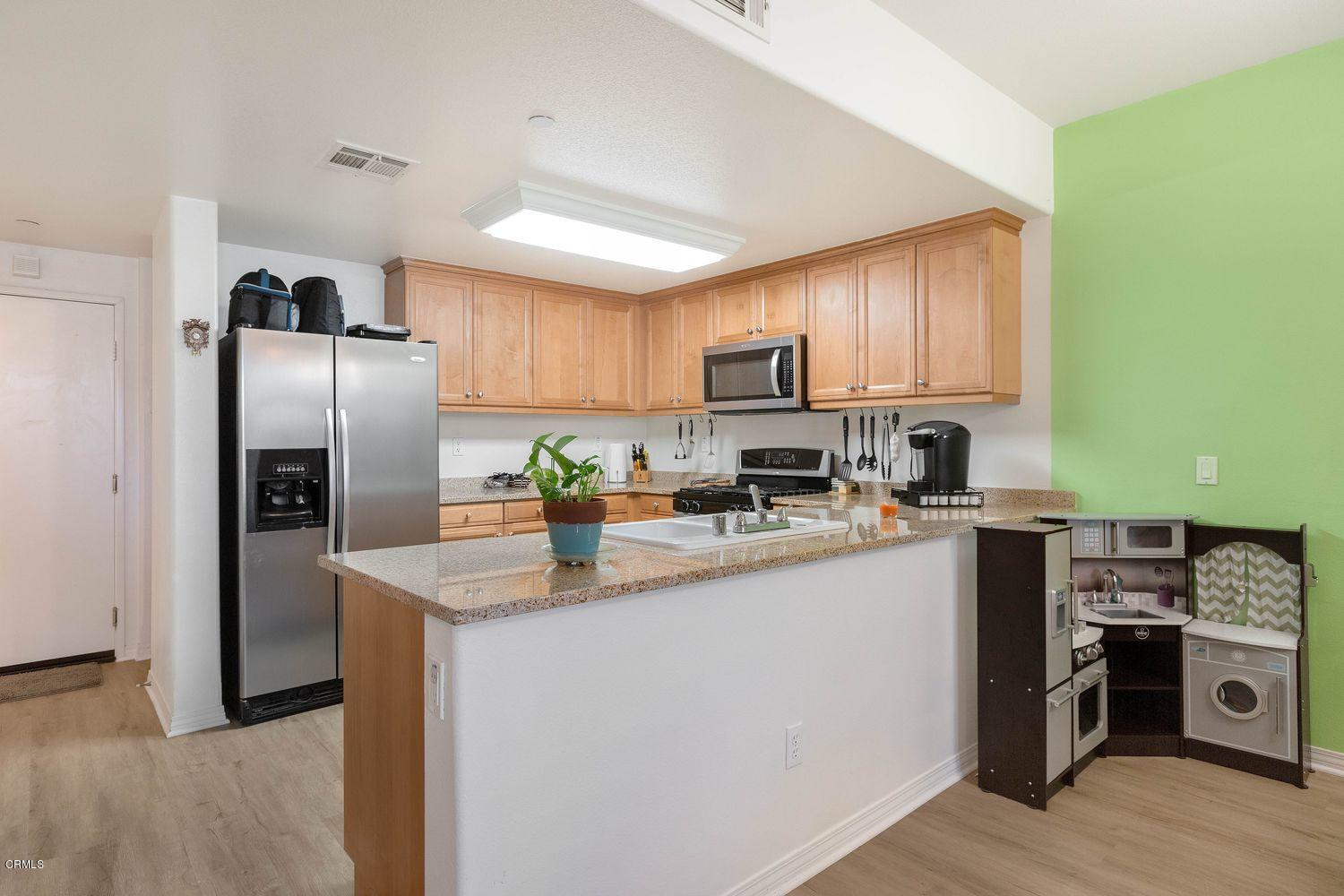 608 Flathead River Street Oxnard, CA 93036 - Photo 8 of 21 a kitchen with granite countertop a refrigerator a stove a sink a counter space and cabinets