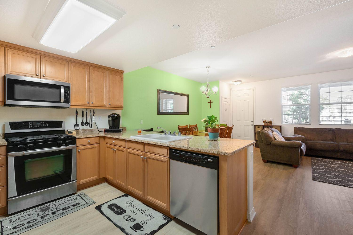 608 Flathead River Street Oxnard, CA 93036 - Photo 10 of 21 a kitchen with stainless steel appliances granite countertop a stove top oven a sink dishwasher a dining table and chairs with wooden floor