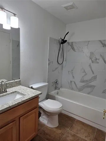 a bathroom with a granite countertop toilet sink and bathtub