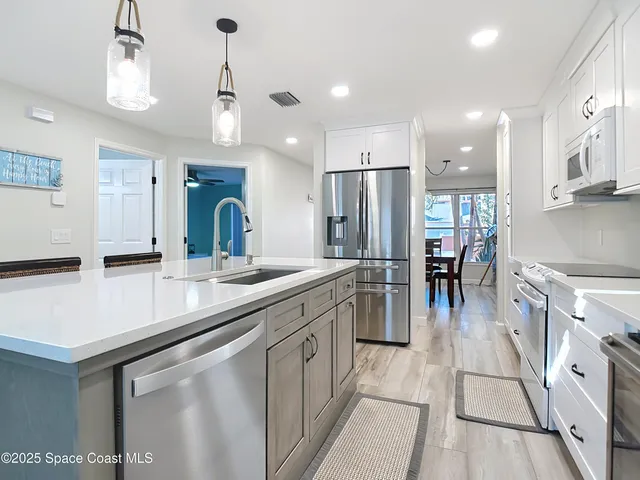 a kitchen with stainless steel appliances kitchen island granite countertop a sink and a refrigerator