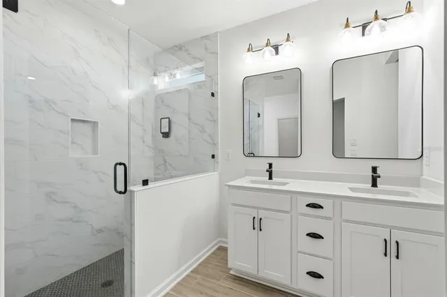 a bathroom with a double vanity sink mirror and shower